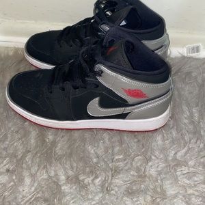 Jordan 1s retro black and silver with red on the bottom .